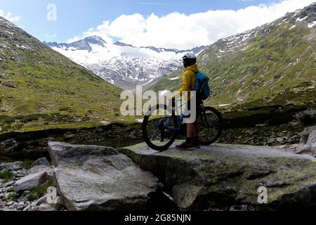 Ragazzo in una gita in mountain bike guardando il ghiacciaio delle montagne nel parco nazionale degli alti tauri, Austria Foto Stock