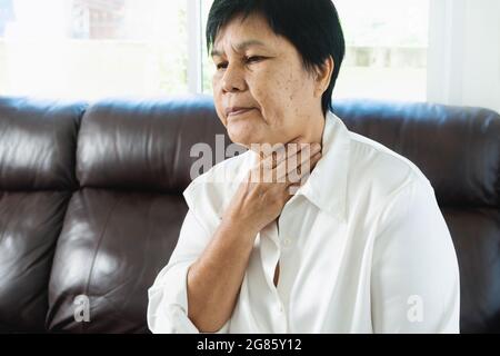 Le donne adulte senior che toccano il collo si sentono malate tosse con Mal di gola Pain.Healthcare e concetto di medicina Foto Stock