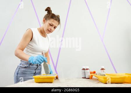 Giovane donna con pittura a pennello parete in una nuova casa. Arredamento in stile domestico Foto Stock