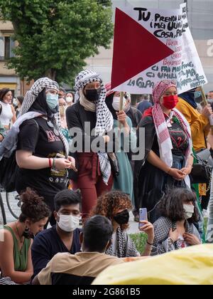 Ragazze con veli sulle loro teste e maschere chirurgiche sui loro volti durante un evento politico in Piazza pubblica con il segno più potente. Foto Stock