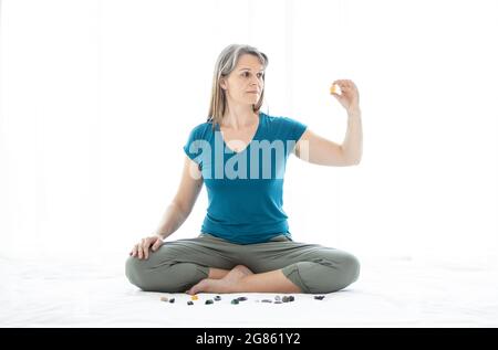 Meditationg donna di mezza età con cristalli Foto Stock