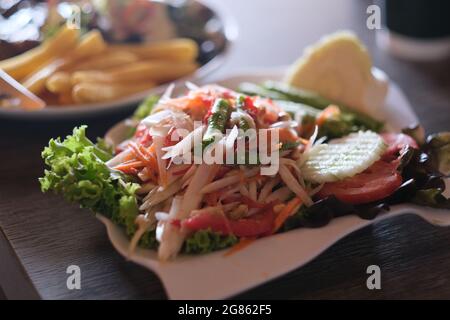 Un piatto pieno di somtam - insalata di cucina tradizionale tailandese che consiste principalmente di papaya verde a fette e verdure varie Foto Stock