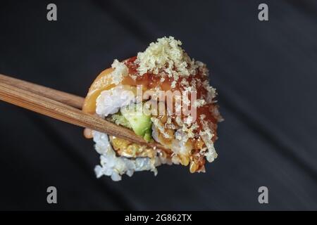 primo piano di bacchette che prendono parte al sushi roll on il ristorante da tavolo / mangiare sushi roll utilizzando bastoncini Foto Stock