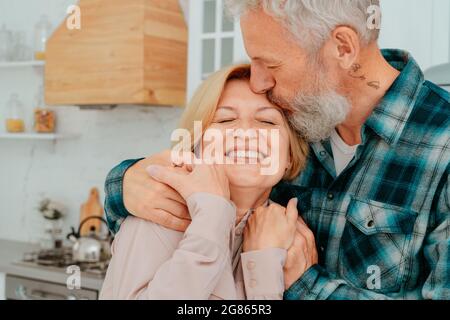 Marito e moglie in pensione si abbracciano a casa Foto Stock