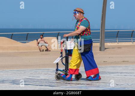 Blackpool, Lancashire. 17 luglio 2021. Il venditore di mongolfiere Clown in un luminoso e soleggiato inizio della giornata nella località nord-occidentale, mentre le persone attraversano e si godono le battute, le citazioni e le parole catch sul marciapiede della Torre Headland commedia Pavement. Credito; MediaWorldImages/AlamyLivenews Foto Stock