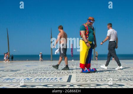 Blackpool, Lancashire. 17 luglio 2021. Il venditore di mongolfiere Clown in un luminoso e soleggiato inizio della giornata nella località nord-occidentale, mentre le persone attraversano e si godono le battute, le citazioni e le parole catch sul marciapiede della Torre Headland commedia Pavement. Credito; MediaWorldImages/AlamyLivenews Foto Stock