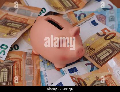 Banca di porcellini circondata da banconote europee da 50, 20 e 10 euro Foto Stock