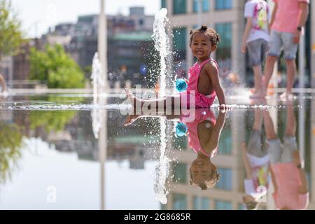 Birmingham, Regno Unito. 17 luglio 2021. Grace, di due anni, ha un po' di tempo nelle fontane della piazza del Centenario di Birmingham. Peter Lopeman/Alamy Live News Foto Stock