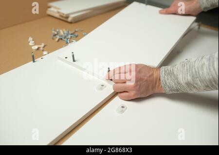 Uomo maestro installare mobili di assemblaggio farlo da soli. Riparazioni a domicilio Foto Stock