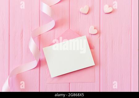 Matrimonio o compleanno mock up scena. Busta vuota aperta con spazio per il testo per il copyspace del biglietto d'auguri. Carta di San Valentino con due cuori in rosa Foto Stock