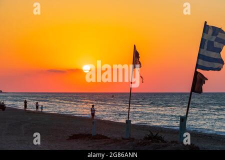 Bandiere di fronte al tramonto più bello a Ialysos Beach sull'isola di Rodi Grecia. Foto Stock