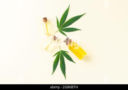 Gruppo di bottiglie di vetro con olio cbd di cannabis, tintura di thc e foglie di canapa. Vista dall'alto, disposizione piatta Foto Stock