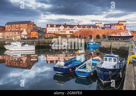 Una bella mattinata ancora con le barche colorate riflesse nel porto di Seahouses sulla costa del Northumberland in Inghilterra, Regno Unito Foto Stock