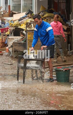 Ahrweiler, Germania. 17 luglio 2021. Un uomo versa acqua su una sedia per liberarla dal fango. La pulizia inizia nelle aree colpite dalla tempesta. Credit: Thomas Frey/dpa/Alamy Live News Foto Stock