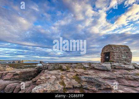 La Powder House a Seahouses sulla costa del Northumberland, con un suggestivo cielo mattutino. Foto Stock