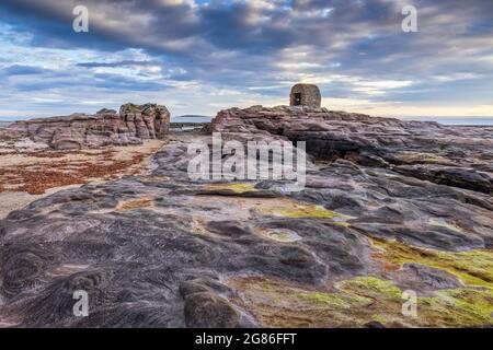 La Powder House a Seahouses sulla costa del Northumberland, con un suggestivo cielo mattutino. Foto Stock