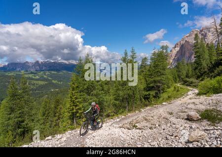 Donna anziana piuttosto attiva che guida la sua mountain bike elettrica fino al Passo della Valparola nelle Dolomiti dell'alta Badia , del Tirolo del Sud e del Trentino Foto Stock