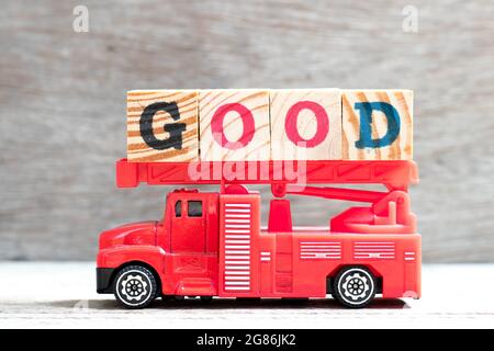 Giocattolo scala fuoco camion tenere il blocco di lettera in parola buono su sfondo di legno Foto Stock