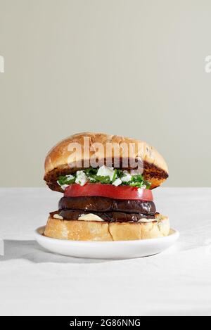 Hamburger con panino vegano con melanzane arrostite, formaggio feta e coriandolo. Concetto di cibo basato su piante Foto Stock