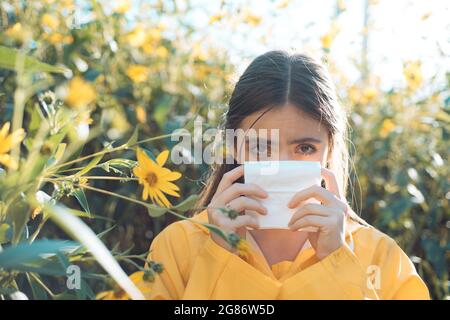 La giovane donna sta andando starnutire. La ragazza soffre di allergia al polline durante la fioritura e utilizza tovaglioli. Bella donna ha avuto influenza starnuti naso. Allergia Foto Stock