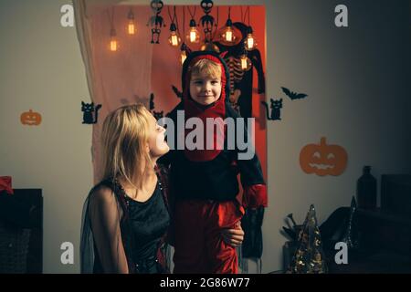 Famiglia divertente madre e bambino figlio divertirsi e celebrare Halloween in costume diavolo. Bella giovane donna con un bambino con zucche autunno. Sorridente Foto Stock