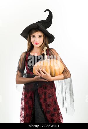 Donna di bellezza in posa con zucca e cappello di Halloween. Ragazza modello attraente in costume di Halloween. Felice giovane donna gotica in costume di Halloween strega Foto Stock