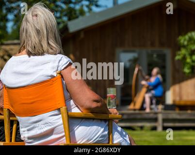 Haddington, East Lothian, Scozia, Regno Unito, 17 luglio 2021. L'arpista celtica Ailie Robertson suona nel giardino murato di Amisfield: Un concerto socialmente distanziato si svolge nel giardino murato gestito da volontari, uno dei più grandi della Scozia. Ailie Robertson è un premiato compositore e performer che suona musica tradizionale e contemporanea arpa Foto Stock