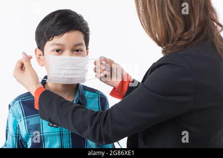 Madre che indossa una maschera chirurgica protettiva sulla faccia del bambino. Idea per amore e cura per prevenire il rischio e il pericolo di bambini e bambini o oronavirus outbera Foto Stock
