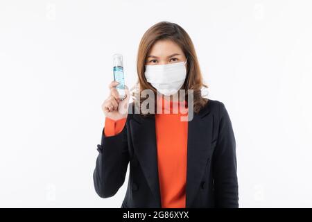 Donna d'affari in tuta nera che indossa una maschera chirurgica protettiva igienica sul viso tenendo in mano il gel detergente lavamani in mano, concetto per prevenire la salute fr Foto Stock