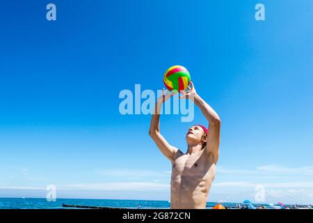 Il ragazzo sportivo gioca a Beach volley a Ost See in una giornata di sole Foto Stock