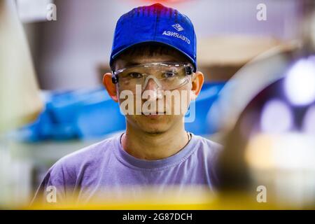 UST'-Kamenogorsk, Kazakhstan, 31,2012 maggio: Asia-auto auto auto-costruzione plant.Abstract ritratto di giovane asiatico in cappuccio blu con logo e bicchieri di plastica. Foto Stock