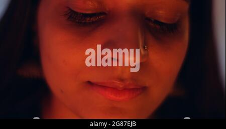 Primo piano di una faccia femminile del Sud asiatico vicino a lume di candela Foto Stock