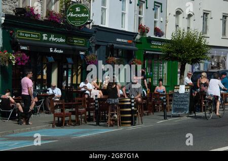 Kenmare Co. Kerry, Irlanda, sabato 17 luglio 2021; le condizioni meteorologiche hanno portato la gente fuori nelle loro droves con temprature in alcune parti del paese, compreso Kenmare, colpendo oltre 30 gradi Celcius. Il bar Horseshoe, che è stato gravemente colpito dalle inondazioni che hanno colpito la città lo scorso luglio, è stato lieto di dare il benvenuto ai clienti al bar. Credit; ed/Alamy Live News Foto Stock