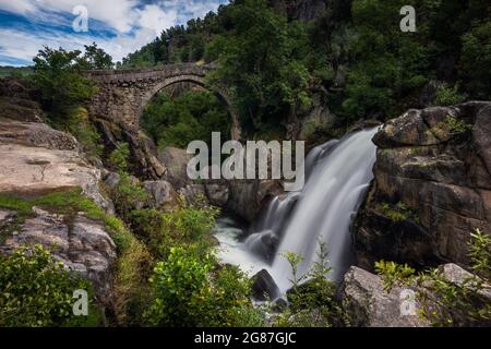 Vista dell'antico Ponte Mizarela o Ponte del Diavolo con una cascata, sul fiume Rabagao, al Parco Nazionale Peneda Geres, in Portogallo Foto Stock