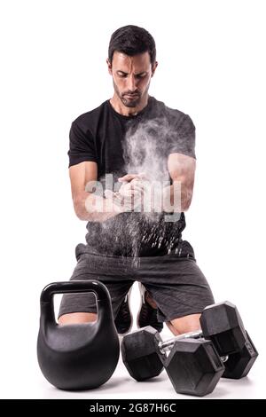 Atleta europeo che si prepara per l'allenamento, aggrappando le mani, con gesso, sollevando una nuvola. Su uno sfondo bianco isolato. Con pesi, Foto Stock