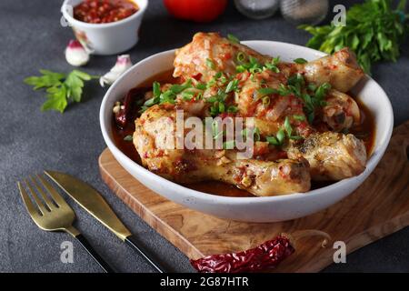 Piatto georgiano di carne chashushuli con pollo e pomodoro su tavola di legno su tavolo grigio scuro. Primo piano Foto Stock