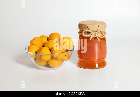 Marmellata di mele cotogne su sfondo bianco. Vasetto di marmellata e frutti di mela cotogna in una ciotola. Foto Stock