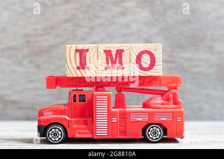 Il camion rosso del fuoco tiene il blocco della lettera nella parola IMO (abbreviazione a mio parere) su sfondo di legno Foto Stock