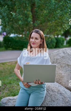 una ragazza in piedi con un computer portatile in natura Foto Stock
