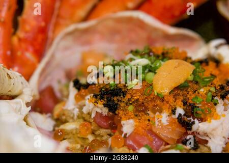 Il riso fritto Taraba nella conchiglia di granchio è composto da tobiko, Ikura roe, salmone e tonno sashimi. Pesce giapponese. Foto Stock