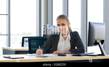 Il personale teen pone con sicurezza prima di iniziare il loro lavoro al mattino. Atmosfera di lavoro mattutina in un ufficio moderno. Foto Stock