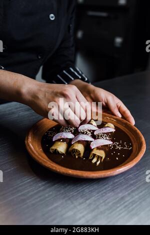 donna messicana che cucina poblano enchiladas cibo tradizionale in un ristorante in Messico Foto Stock