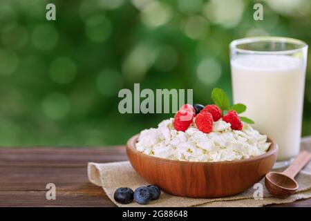 yogurt in vetro e formaggio di cottage con frutti di bosco freschi a tavola all'aperto Foto Stock