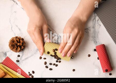 Donna che fa candele di cera su sfondo chiaro Foto Stock