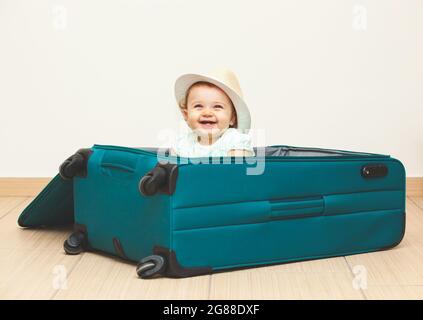 Bambina seduta in valigia sul pavimento con sfondo vuoto. Foto Stock
