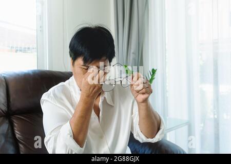 Vecchia donna rimozione degli occhiali, massaggiare gli occhi dopo aver letto il libro cartaceo. provare disagio a causa di lunghi indossando occhiali, affetti da occhi Foto Stock