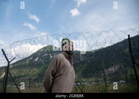 Bandipora, India. 18 luglio 2021. Un uomo cammina lungo una recinzione di confine del rasoio nel villaggio di Chorwan.Gurez si trova lungo il LOC nella parte settentrionale del Kashmir. Gurez è una valle situata nell'alta Himalaya, a circa 123 chilometri da Srinagar nel nord del Kashmir. A circa 2,400 metri sul livello del mare, la valle è circondata da montagne innevate. Credit: SOPA Images Limited/Alamy Live News Foto Stock