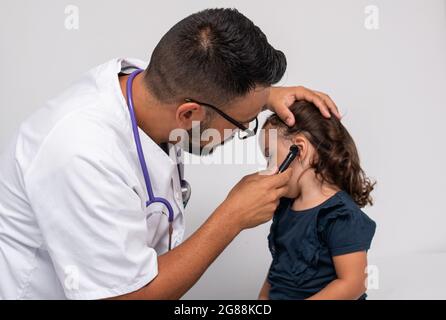 Pediatra caucasica trentenne che esamina le orecchie del suo paziente, una bambina caucasica di tre anni. Concetto pediatrico. Foto Stock