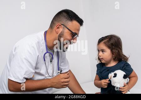 Medico pediatrico che esamina la gola di una bambina di 3 anni Foto Stock