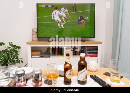 un televisore widescreen che mostra Harry Kane sulla palla durante la finale della competizione calcistica UEFA Euro 2020 con Inghilterra e Italia, con birre sul tavolo. REGNO UNITO Foto Stock